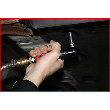 Eine Person hält einen schwarzen, rot umrandeten Druckluftschrauber. Ein Metallschlauch ist mit dem Werkzeug verbunden.